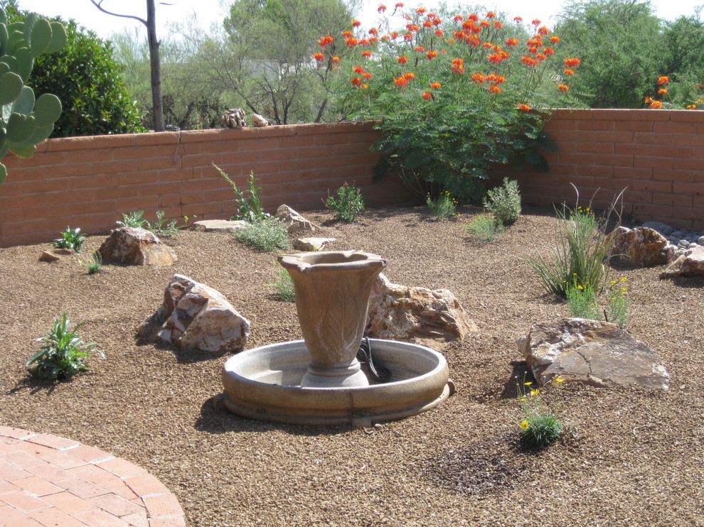 Mid-sized backyard full sun xeriscape in Phoenix with a water feature and natural stone pavers for spring.