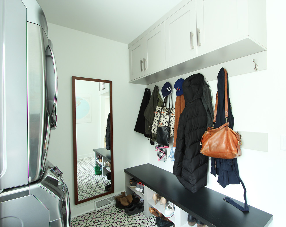 This is an example of a small transitional single-wall dedicated laundry room in Other with recessed-panel cabinets, grey cabinets, quartz benchtops, white walls, porcelain floors, a stacked washer and dryer and multi-coloured floor.