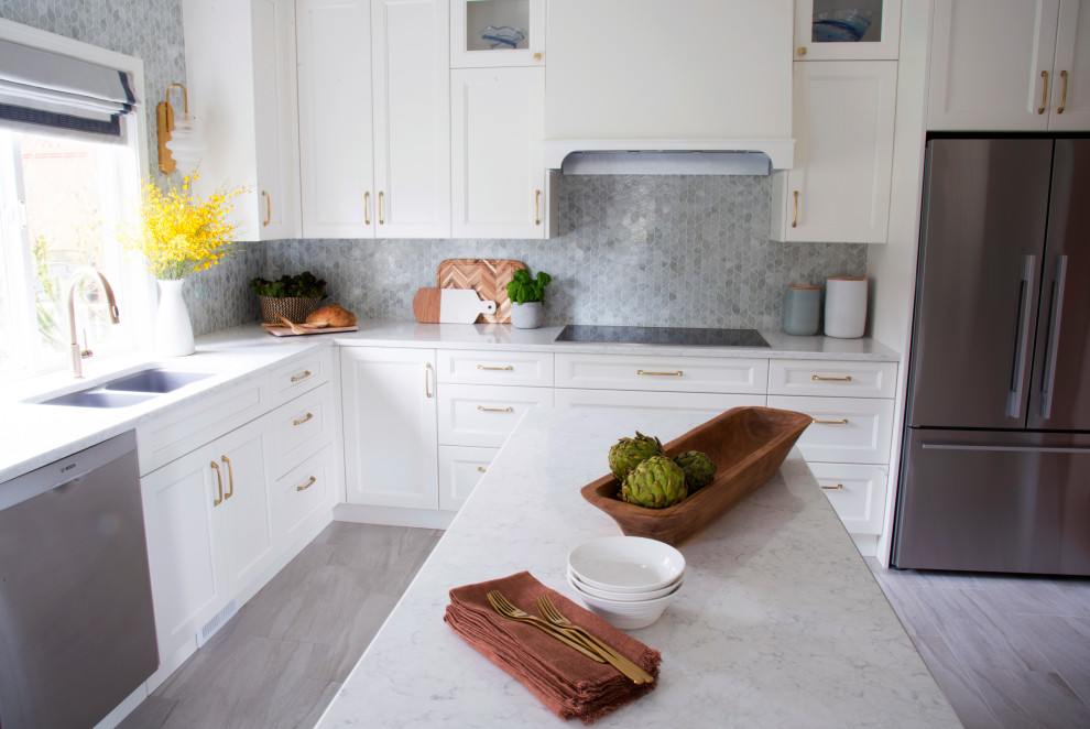 Large transitional u-shaped porcelain tile and gray floor kitchen photo in Vancouver with an undermount sink, shaker cabinets, white cabinets, quartz countertops, white backsplash, glass tile backsplash, stainless steel appliances, an island and white countertops