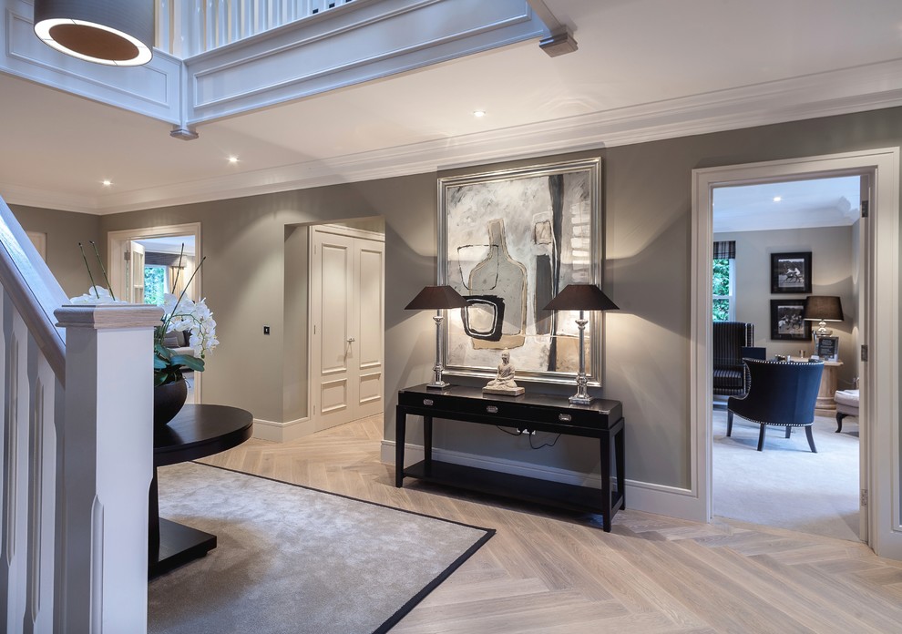 Example of a large transitional light wood floor and beige floor foyer design with gray walls