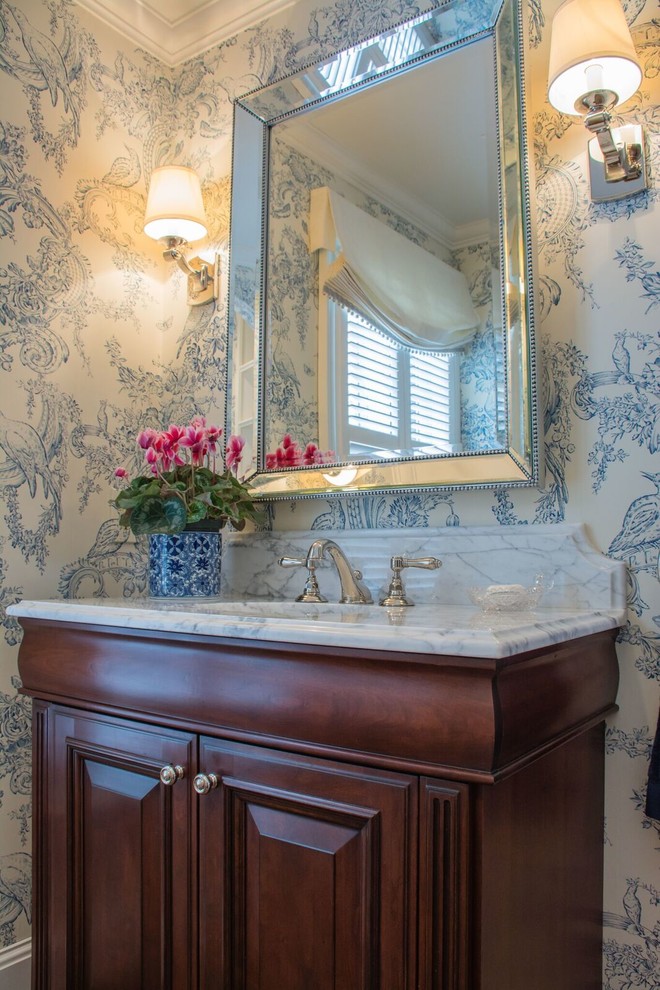 Inspiration for a mid-sized traditional powder room in Cleveland with furniture-like cabinets, medium wood cabinets, a one-piece toilet, blue walls and marble benchtops.