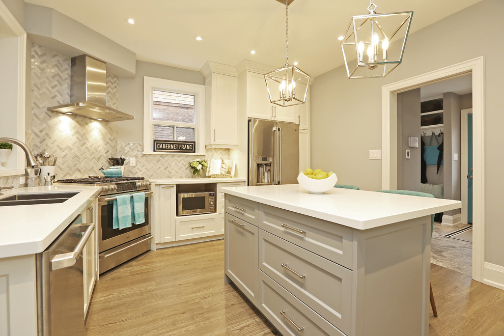 Inspiration for a mid-sized transitional u-shaped light wood floor and brown floor enclosed kitchen remodel in Toronto with an undermount sink, shaker cabinets, white cabinets, solid surface countertops, gray backsplash, stainless steel appliances, an island and white countertops