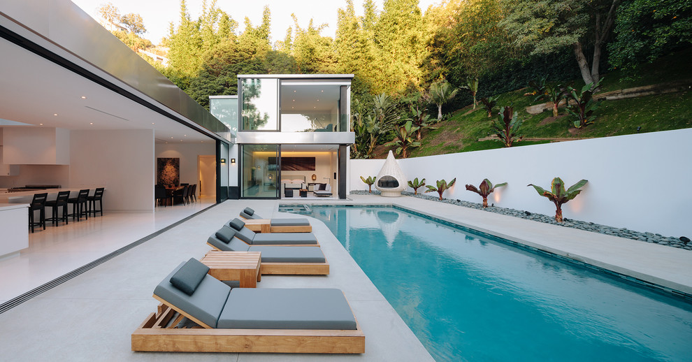 Photo of a large contemporary backyard rectangular infinity pool in Los Angeles with a pool house.