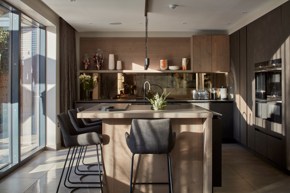 Immagine di una cucina contemporanea con lavello sottopiano, ante lisce, ante in legno bruno, elettrodomestici neri, pavimento in cemento, pavimento grigio e top beige