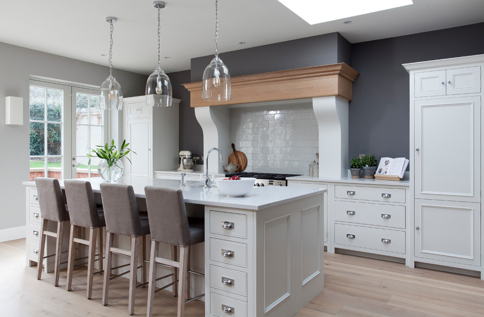 This is an example of a large traditional single-wall eat-in kitchen in Dublin with flat-panel cabinets, grey cabinets, white splashback, subway tile splashback, laminate floors, with island and beige floor.