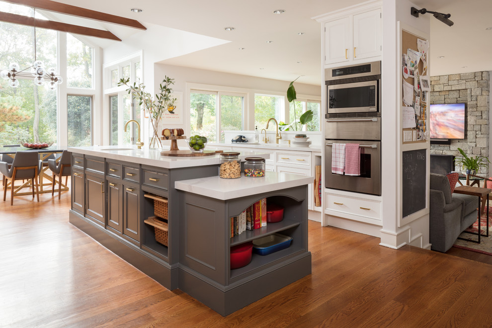 This is an example of a transitional galley open plan kitchen in Other with an undermount sink, recessed-panel cabinets, grey cabinets, stainless steel appliances, medium hardwood floors, with island and brown floor.