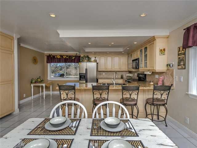 Inspiration for a large transitional u-shaped ceramic tile open concept kitchen remodel in Denver with an undermount sink, raised-panel cabinets, beige cabinets, granite countertops, beige backsplash, terra-cotta backsplash and black appliances