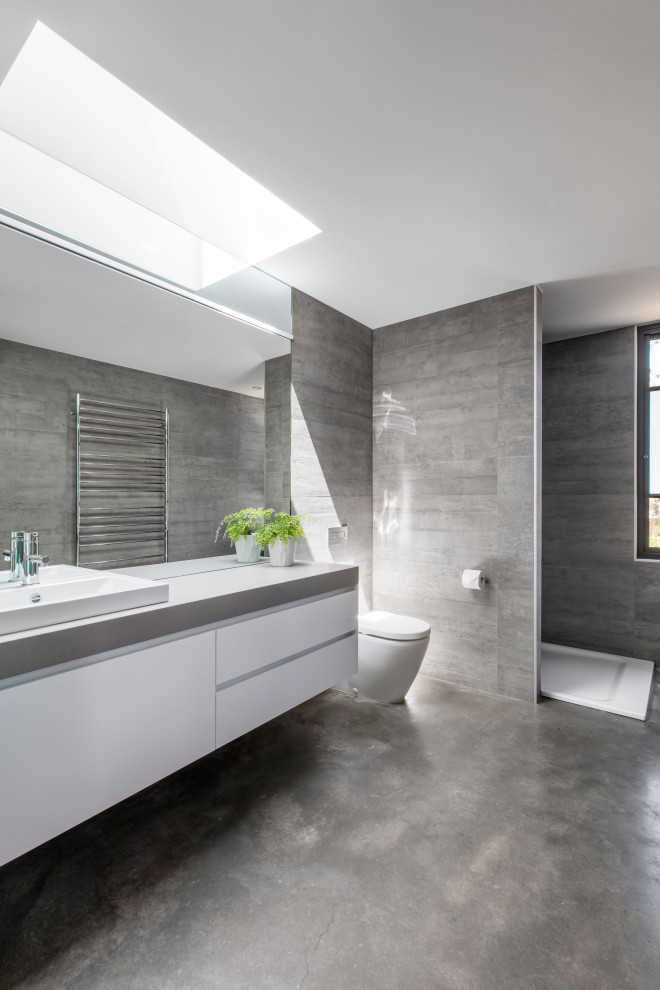 This is an example of a mid-sized modern bathroom in Melbourne with white cabinets, an open shower, a one-piece toilet, gray tile, ceramic tile, grey walls, concrete floors, a drop-in sink, engineered quartz benchtops, grey floor, an open shower, grey benchtops, a single vanity and a floating vanity.