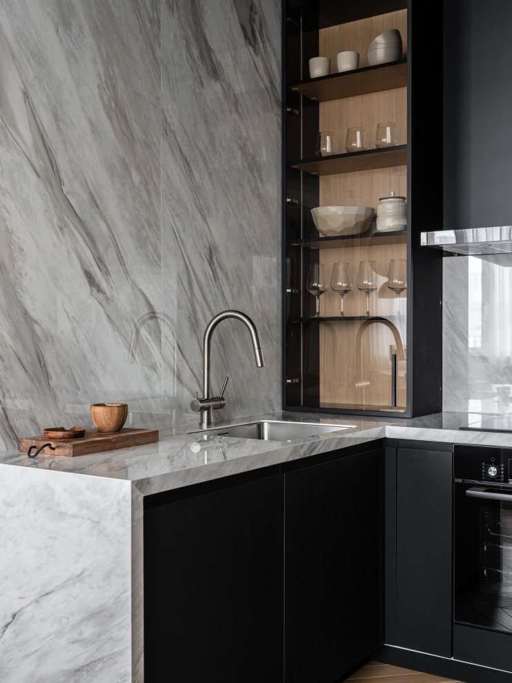 Immagine di una cucina design con lavello sottopiano, ante lisce, ante nere, paraspruzzi grigio e top grigio