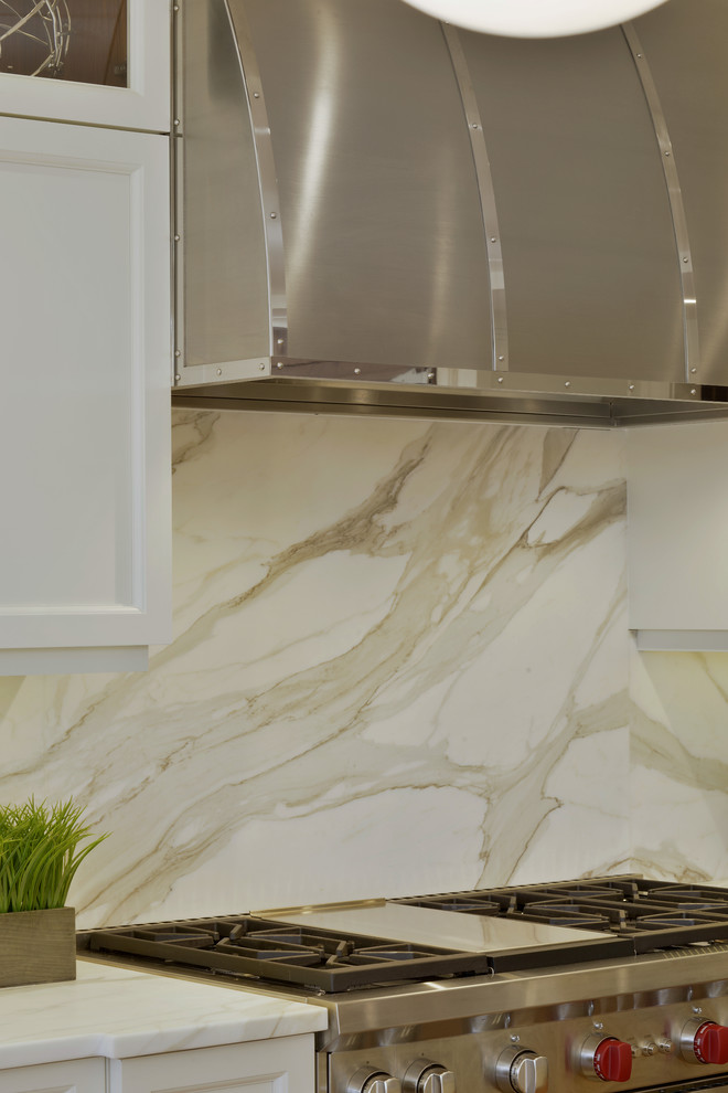Inspiration for a large transitional l-shaped medium tone wood floor and brown floor open concept kitchen remodel in New York with an undermount sink, shaker cabinets, white cabinets, marble countertops, white backsplash, marble backsplash, paneled appliances and an island