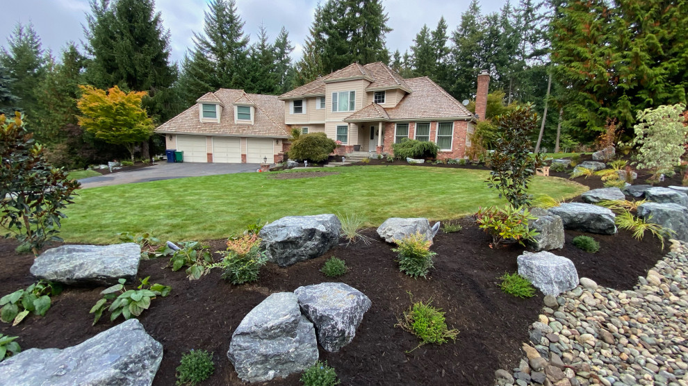 Inspiration for a large sloped partial sun garden in Seattle with with rock feature and mulch.
