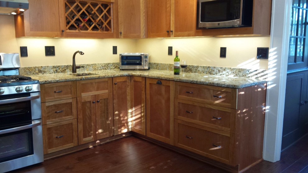 Eat-in kitchen - mid-sized dark wood floor eat-in kitchen idea with a single-bowl sink, flat-panel cabinets, medium tone wood cabinets, granite countertops and stainless steel appliances
