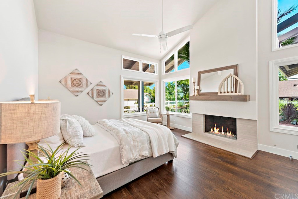 Photo of a mid-sized transitional guest bedroom in Orange County with grey walls, laminate floors, a standard fireplace, a tile fireplace surround and brown floor.