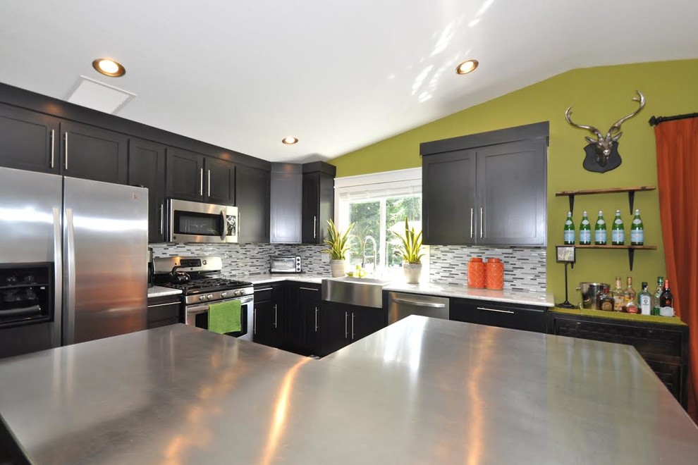 Example of a large transitional l-shaped dark wood floor eat-in kitchen design in Seattle with a farmhouse sink, shaker cabinets, black cabinets, stainless steel countertops, multicolored backsplash, matchstick tile backsplash, stainless steel appliances and an island
