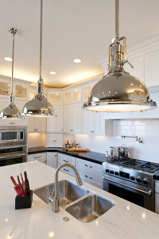 Inspiration for a large arts and crafts l-shaped eat-in kitchen in Salt Lake City with an undermount sink, recessed-panel cabinets, white cabinets, marble benchtops, white splashback, subway tile splashback, stainless steel appliances, dark hardwood floors and with island.