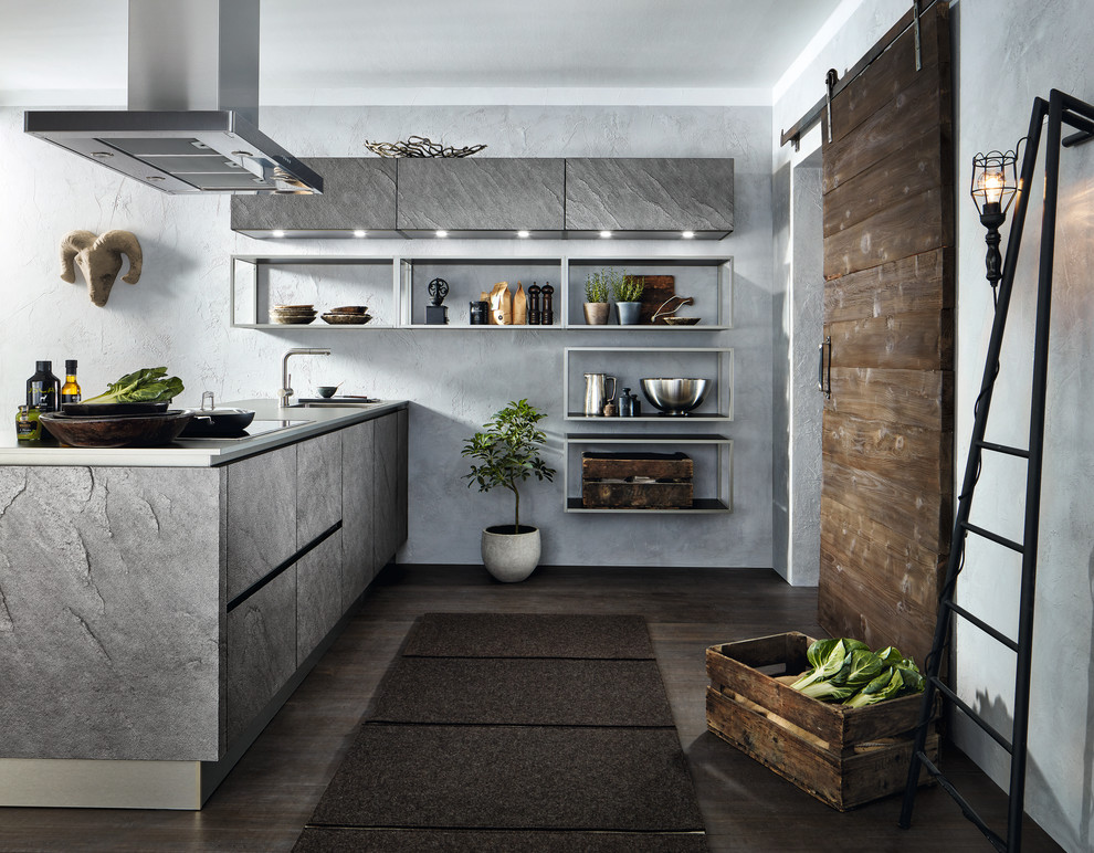 Inspiration for an expansive industrial single-wall open plan kitchen in Dresden with a drop-in sink, flat-panel cabinets, grey cabinets, solid surface benchtops, grey splashback, stone slab splashback, stainless steel appliances, dark hardwood floors, with island and brown floor.