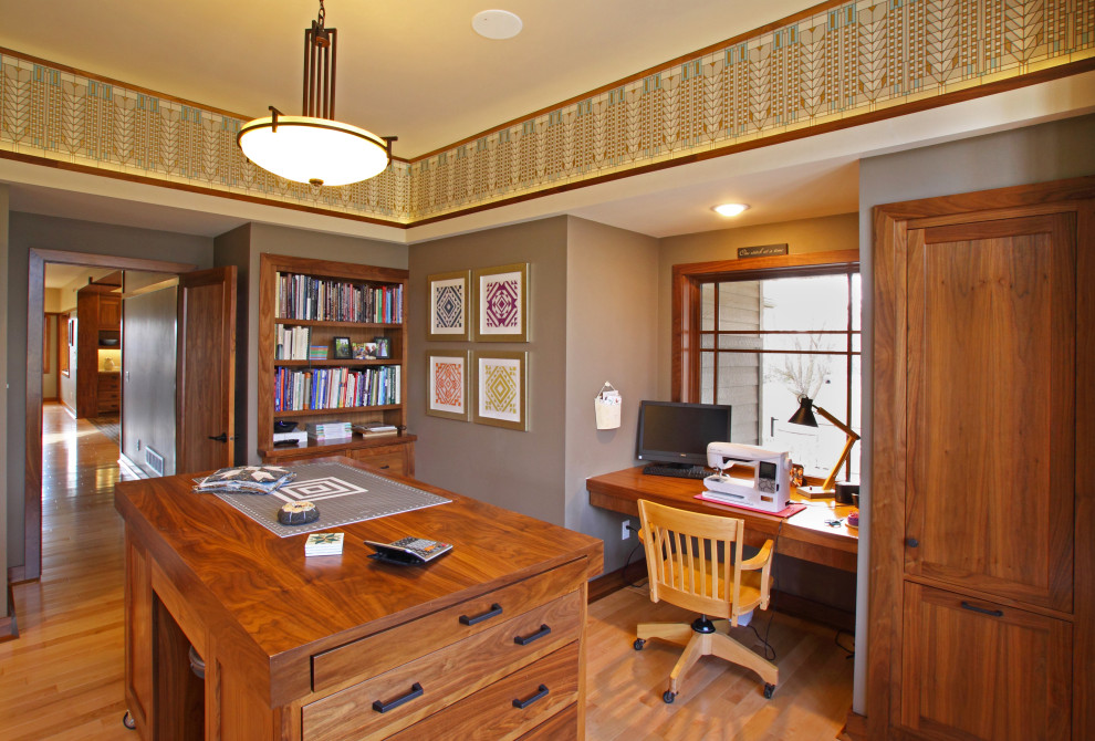 Imagen de sala de manualidades moderna de tamaño medio con paredes grises, suelo de madera clara, escritorio empotrado y suelo marrón