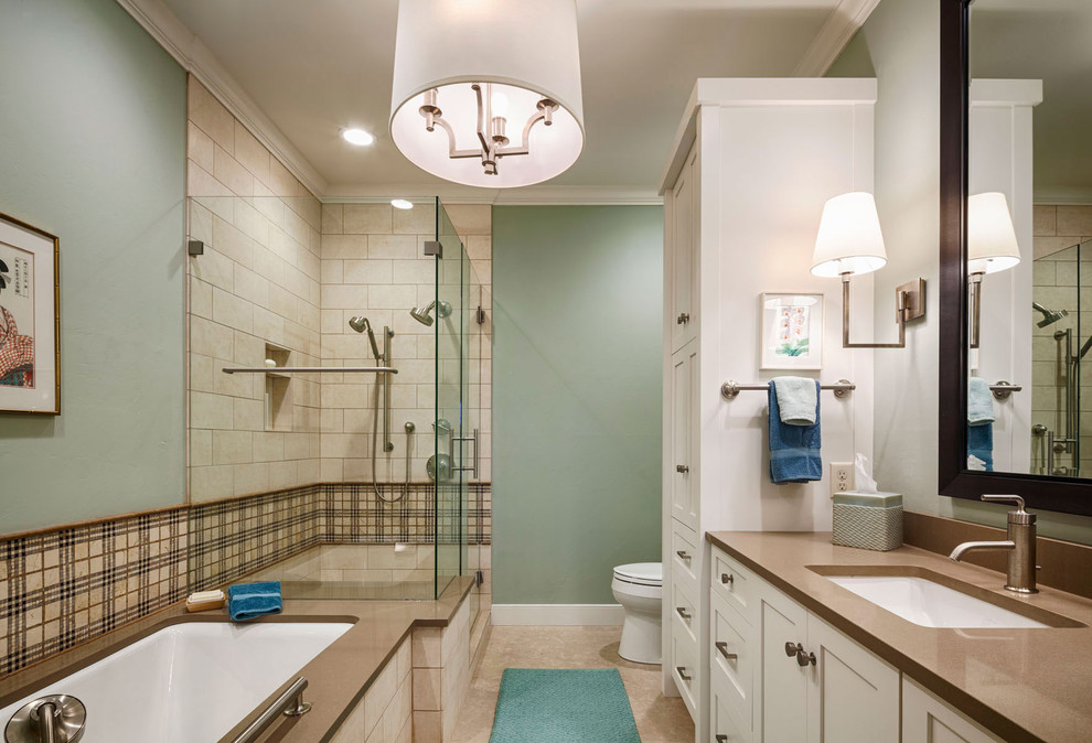 This is an example of a mid-sized traditional bathroom in Milwaukee with shaker cabinets, white cabinets, an undermount tub, a corner shower, a two-piece toilet, beige tile, stone tile, green walls, an undermount sink, engineered quartz benchtops, brown floor and a hinged shower door.