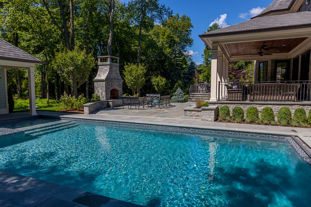 Photo of a large traditional backyard custom-shaped lap pool in New York with a water feature and concrete pavers.