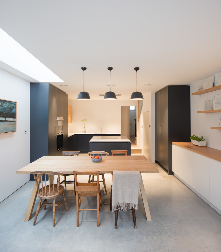 This is an example of a large scandinavian kitchen/dining combo in London with white walls, concrete floors, no fireplace and grey floor.
