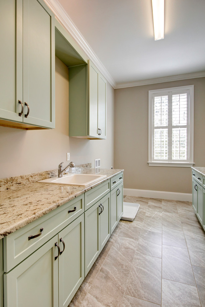 Photo of a large traditional galley dedicated laundry room in Jacksonville with a drop-in sink, shaker cabinets, green cabinets, granite benchtops, brown walls, porcelain floors, brown floor and brown benchtop.