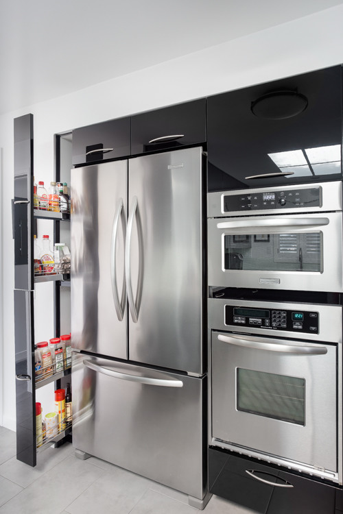 Contemporary u-shaped kitchen in San Francisco with an undermount sink, flat-panel cabinets, black cabinets, white splashback, glass sheet splashback, stainless steel appliances and a peninsula.