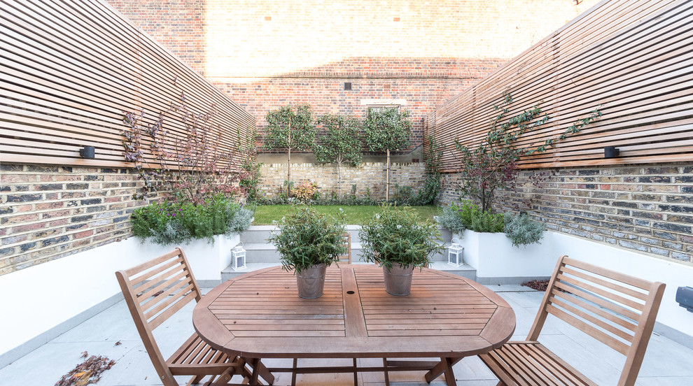 This is an example of a mid-sized traditional backyard patio in London.