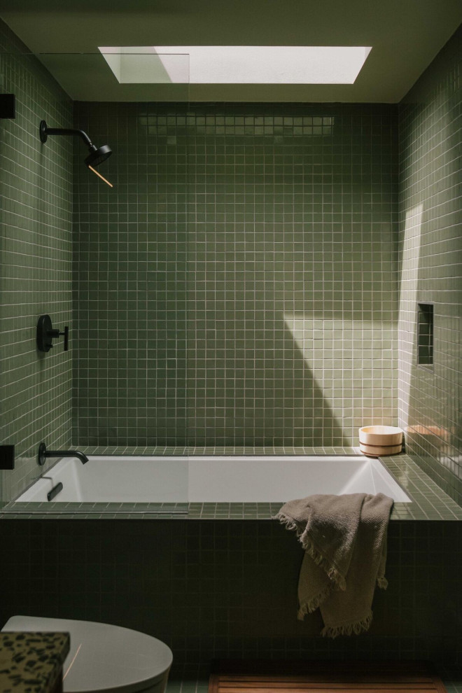 Photo of a modern bathroom in Los Angeles with a drop-in tub, green tile, ceramic tile, green walls, ceramic floors and green floor.