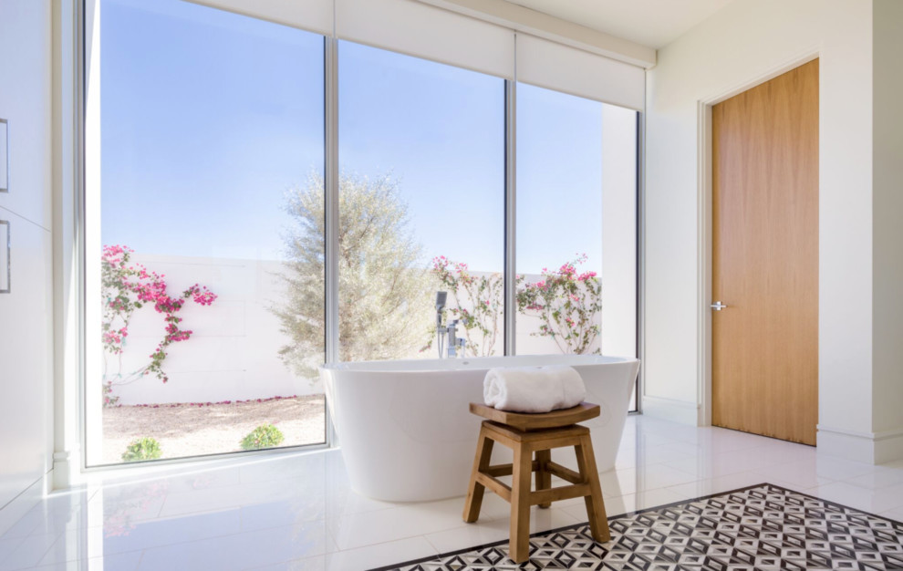 Photo of a large modern master bathroom in Los Angeles with flat-panel cabinets, white cabinets, a freestanding tub, beige tile, stone tile, beige walls, porcelain floors, an undermount sink, engineered quartz benchtops and white floor.