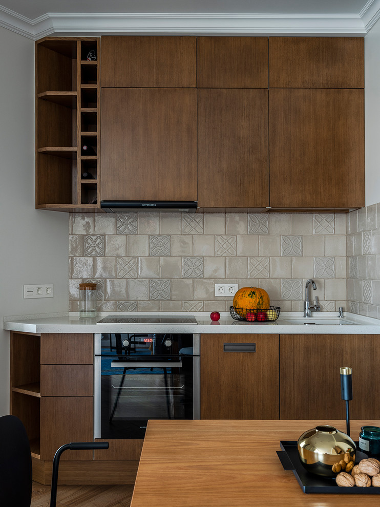 Mid-sized contemporary single-wall kitchen in Moscow with a single-bowl sink, flat-panel cabinets, medium wood cabinets, solid surface benchtops, beige splashback, ceramic splashback, black appliances, medium hardwood floors, no island, brown floor and white benchtop.