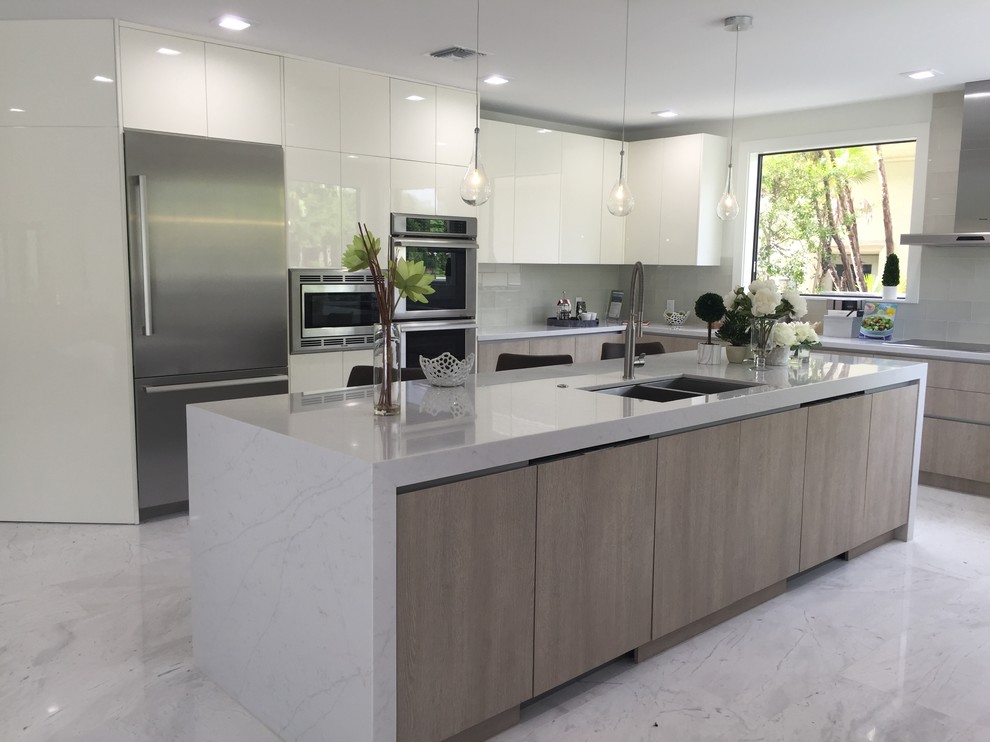 Exempel på ett stort modernt kök, med en undermonterad diskho, släta luckor, skåp i ljust trä, bänkskiva i kvarts, vitt stänkskydd, stänkskydd i glaskakel, rostfria vitvaror, marmorgolv, en köksö och vitt golv