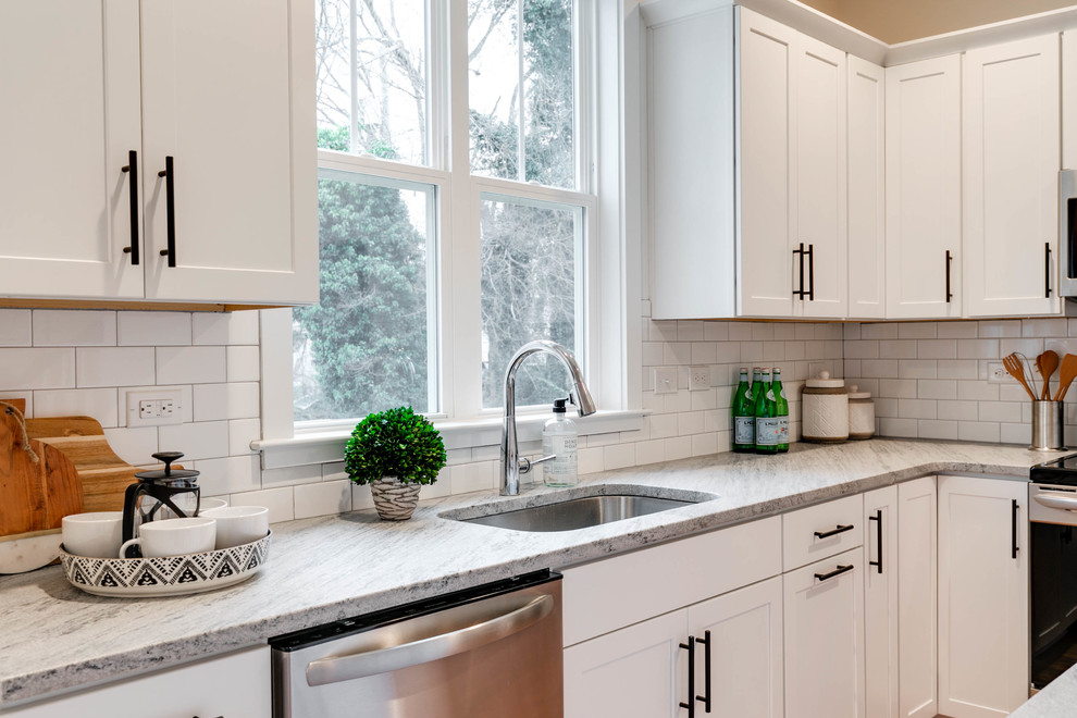 Mid-sized scandinavian l-shaped eat-in kitchen in Richmond with an undermount sink, recessed-panel cabinets, white cabinets, granite benchtops, white splashback, ceramic splashback, stainless steel appliances, light hardwood floors and with island.