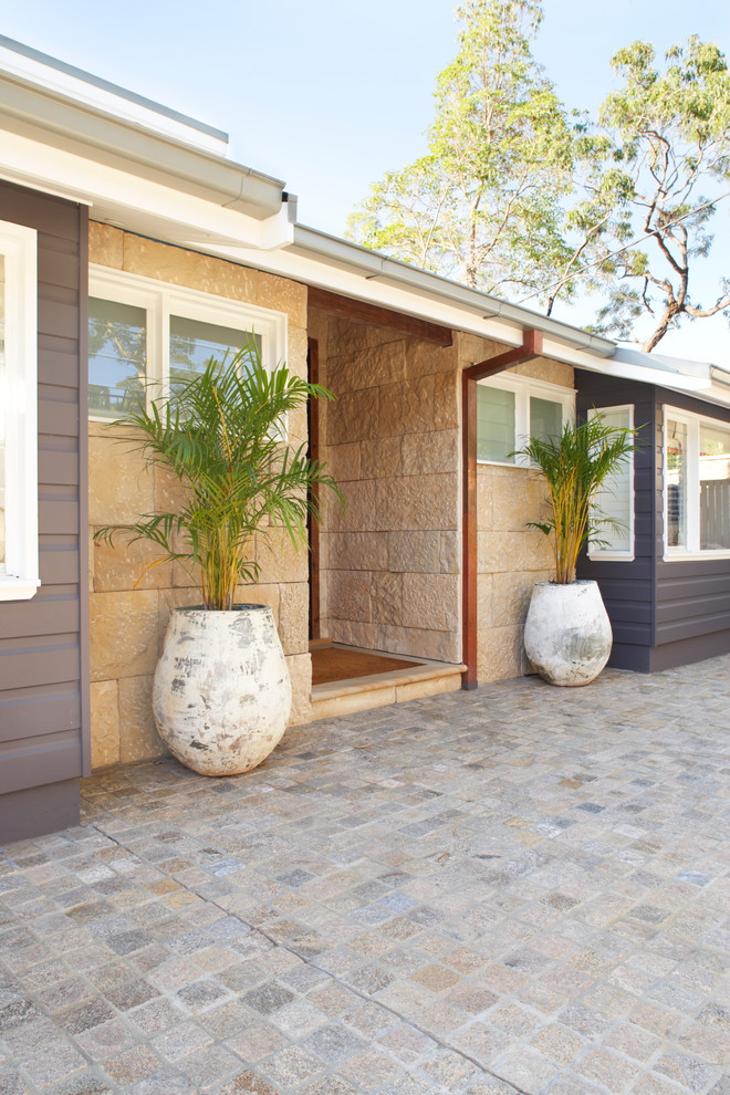 This is an example of a large traditional front yard driveway in Sydney with natural stone pavers.