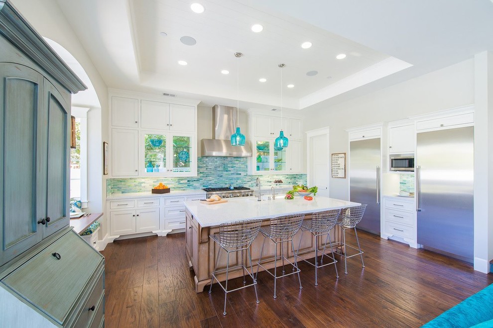 Inspiration for a large beach style l-shaped open plan kitchen in Los Angeles with recessed-panel cabinets, white cabinets, multi-coloured splashback, stainless steel appliances, with island, mosaic tile splashback, quartz benchtops, an undermount sink, dark hardwood floors, brown floor and white benchtop.