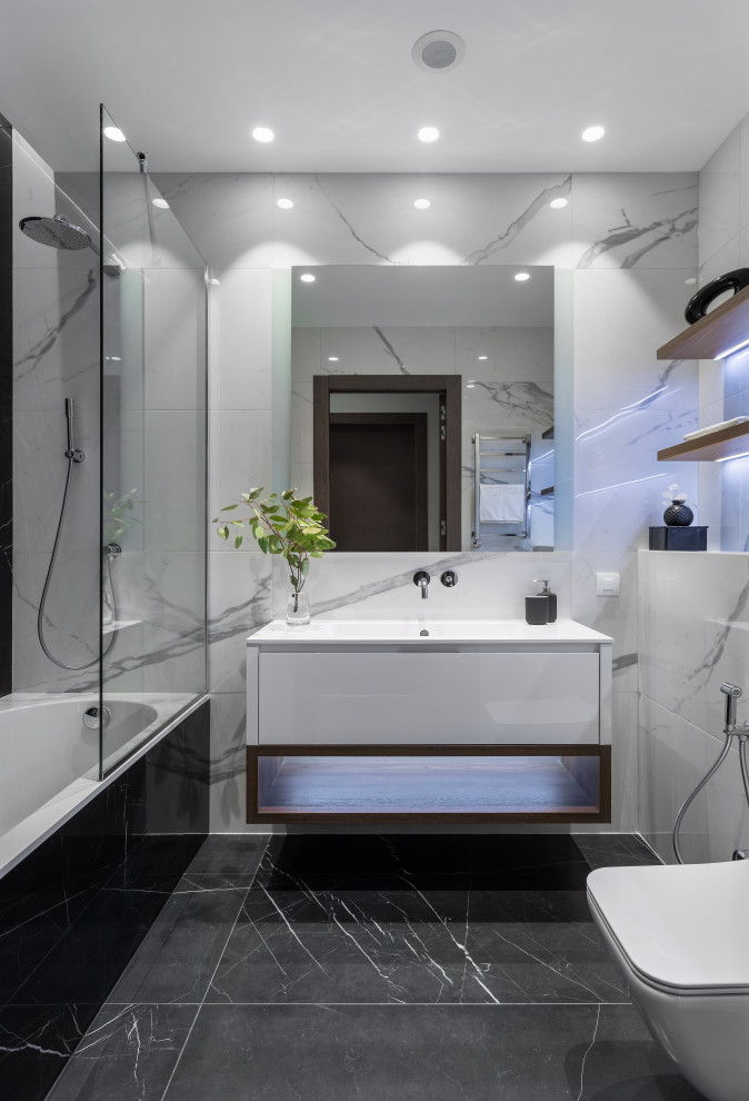 Idéer för funkis vitt badrum, med släta luckor, vita skåp, ett badkar i en alkov, en dusch/badkar-kombination, vit kakel, ett integrerad handfat, svart golv och med dusch som är öppen