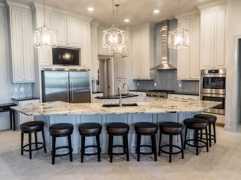 Inspiration for a large transitional u-shaped eat-in kitchen remodel with an undermount sink, raised-panel cabinets, white cabinets, granite countertops, gray backsplash, ceramic backsplash, stainless steel appliances and two islands