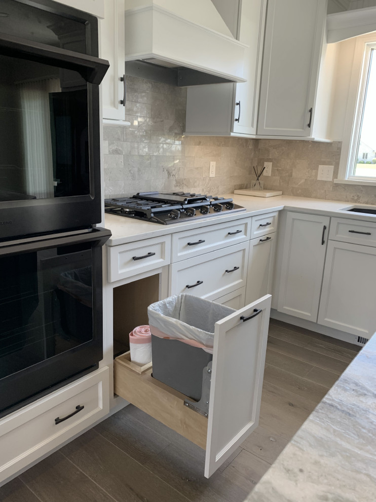 Eat-in kitchen - large transitional l-shaped vinyl floor and gray floor eat-in kitchen idea with an undermount sink, recessed-panel cabinets, white cabinets, quartz countertops, gray backsplash, ceramic backsplash, stainless steel appliances, an island and white countertops