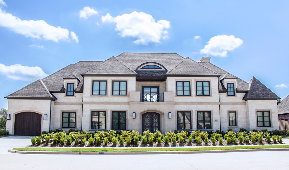 This is an example of a large transitional two-storey white house exterior in Dallas with stone veneer and a gable roof.
