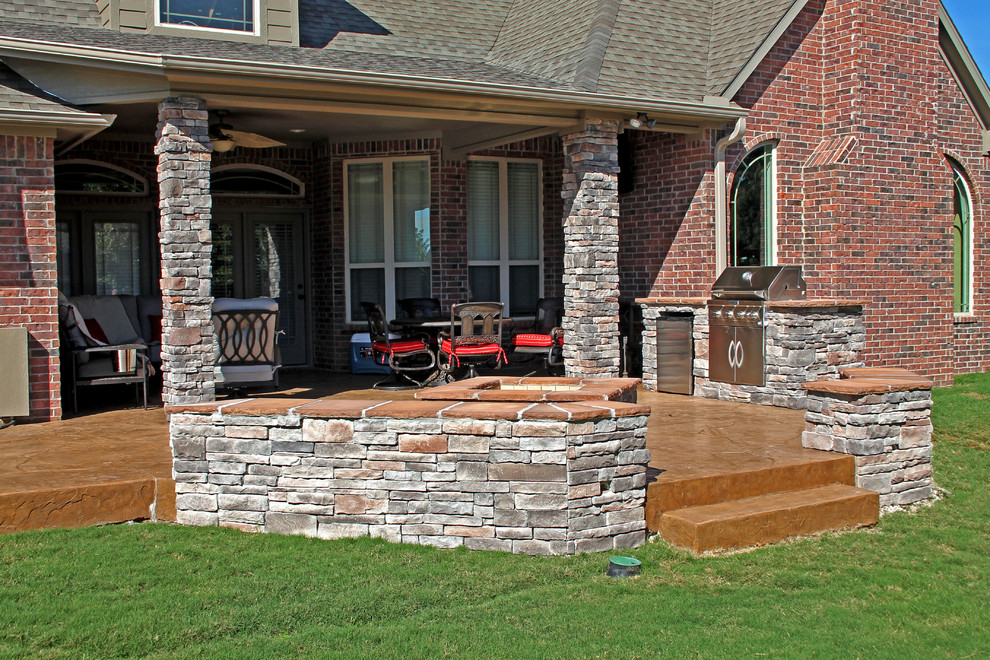 Inspiration for a mid-sized transitional backyard patio in Other with an outdoor kitchen, stamped concrete and a roof extension.