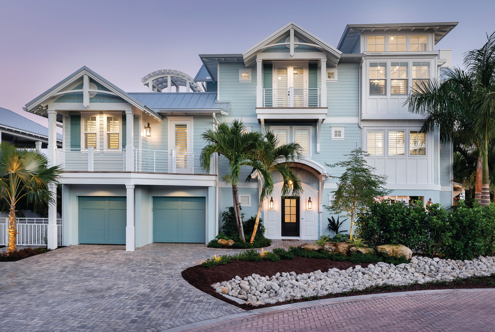 Photo of a beach style two-storey blue house exterior in Tampa with mixed siding, a gable roof and a metal roof.