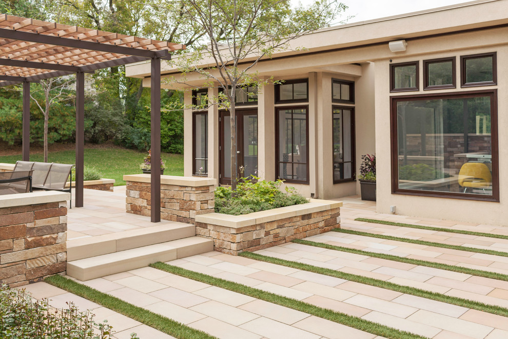 This is an example of a contemporary courtyard patio in Minneapolis with natural stone pavers and a pergola.