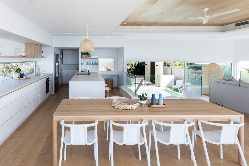 Design ideas for a mid-sized contemporary open plan dining in Sunshine Coast with white walls, medium hardwood floors and brown floor.