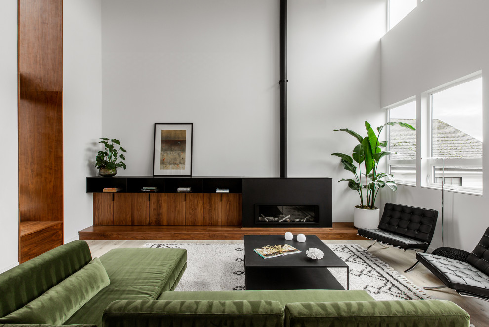 This is an example of a large midcentury open concept living room in Seattle with white walls, light hardwood floors, a ribbon fireplace, a metal fireplace surround, no tv and vaulted.