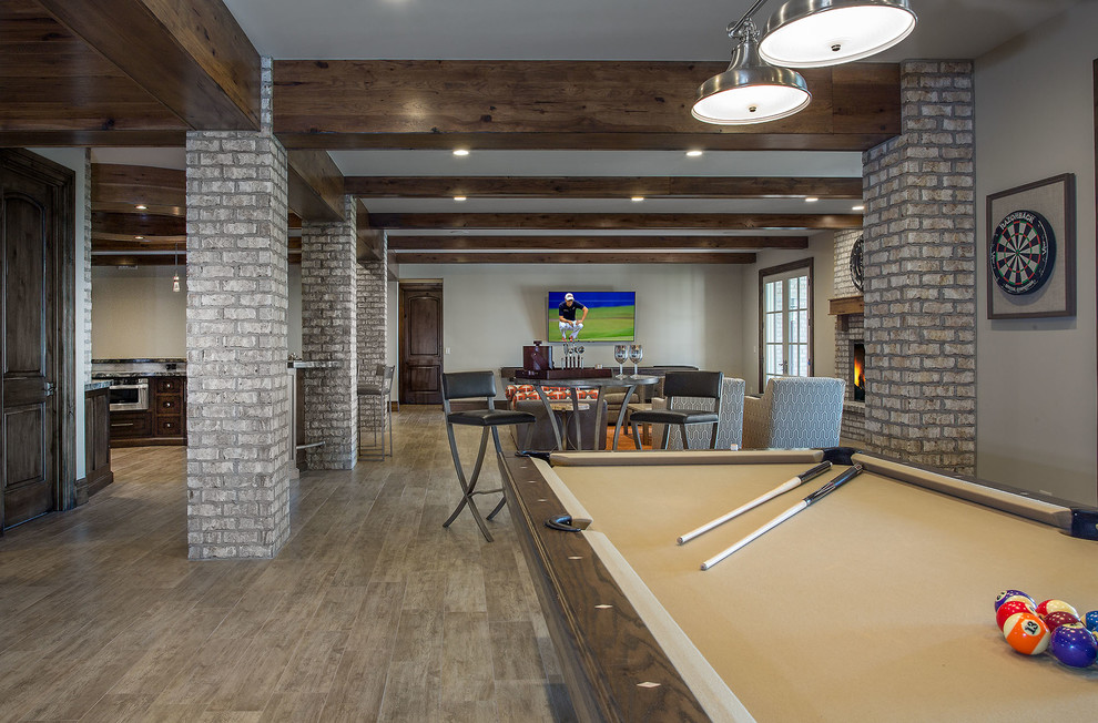 This is an example of an expansive traditional look-out basement in Salt Lake City with grey walls, medium hardwood floors, a standard fireplace, a brick fireplace surround and brown floor.