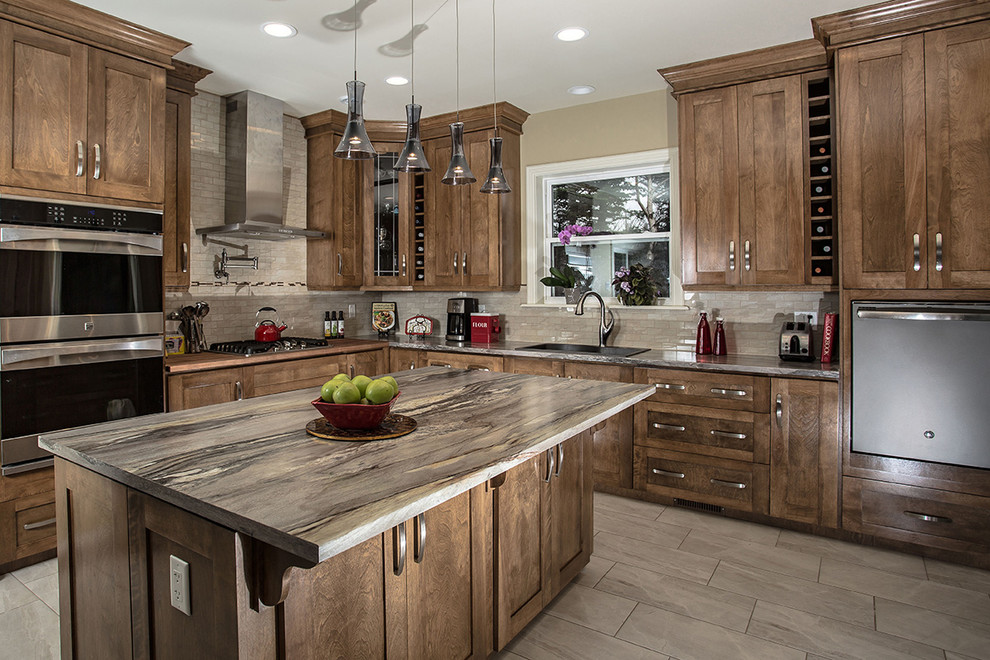Example of a large mountain style u-shaped ceramic tile eat-in kitchen design with shaker cabinets, brown cabinets, beige backsplash, stainless steel appliances and an island