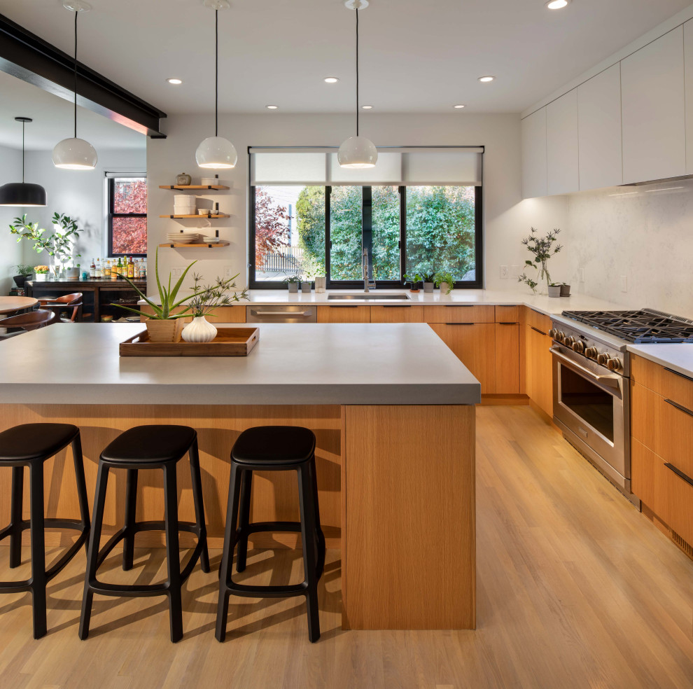 Photo of a mid-sized contemporary l-shaped open plan kitchen in DC Metro with flat-panel cabinets, quartz benchtops, white splashback, stainless steel appliances, with island, grey benchtop, an undermount sink, medium wood cabinets, medium hardwood floors and brown floor.