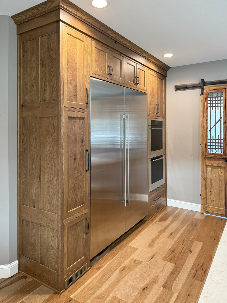Eat-in kitchen - large transitional l-shaped light wood floor eat-in kitchen idea with a farmhouse sink, beaded inset cabinets, quartz countertops, white backsplash, subway tile backsplash, stainless steel appliances and an island