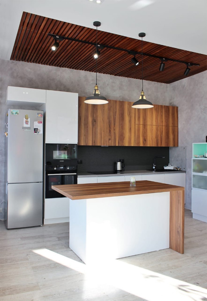 Photo of a large contemporary single-wall eat-in kitchen in Novosibirsk with an undermount sink, flat-panel cabinets, white cabinets, wood benchtops, black splashback, mosaic tile splashback, black appliances, vinyl floors, with island, beige floor and brown benchtop.