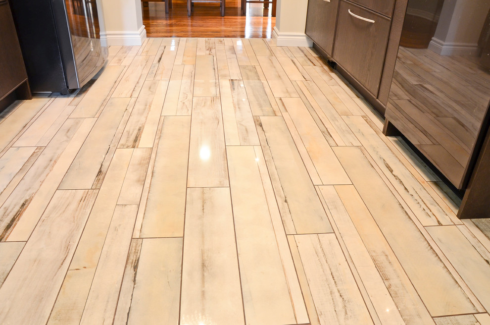 Inspiration for a mid-sized transitional galley porcelain tile kitchen remodel in Ottawa with an undermount sink, glass-front cabinets, brown cabinets, quartz countertops, brown backsplash, glass sheet backsplash and stainless steel appliances