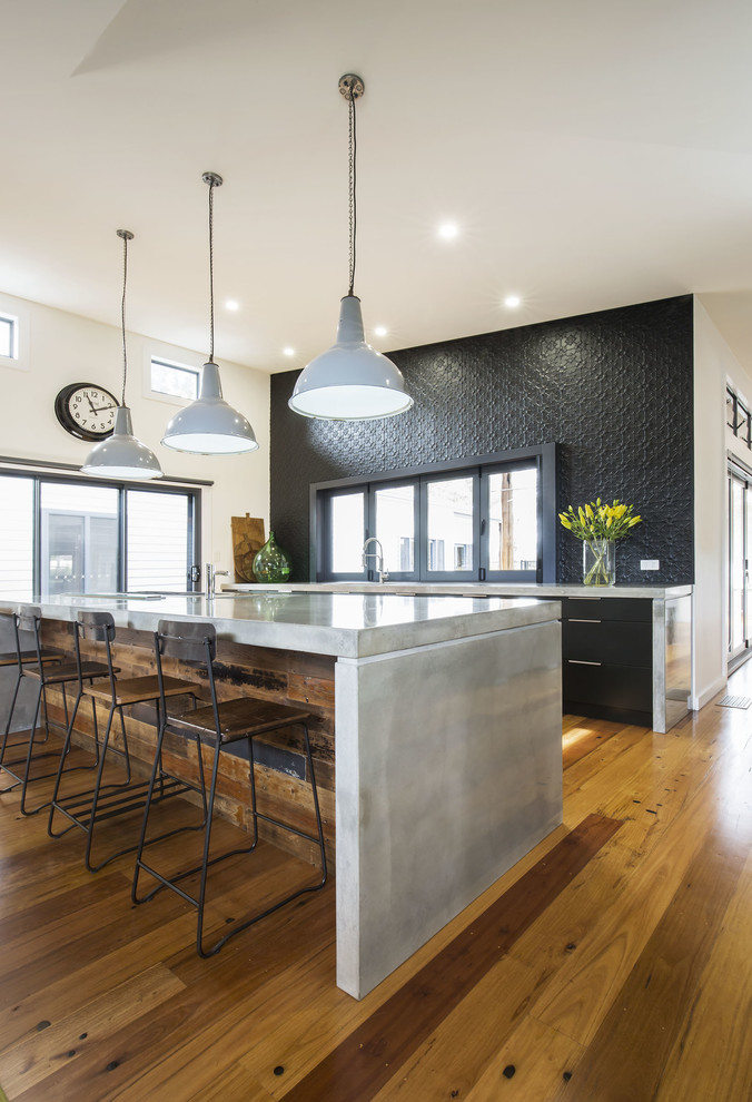 Design ideas for a mid-sized contemporary single-wall open plan kitchen in Sydney with an undermount sink, flat-panel cabinets, black cabinets, concrete benchtops, black splashback, metal splashback, stainless steel appliances, medium hardwood floors and with island.